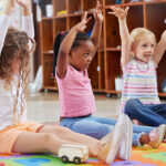 Three children raising their hands above their heads