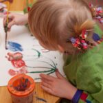 a little girl painting flowers with a paintbrush